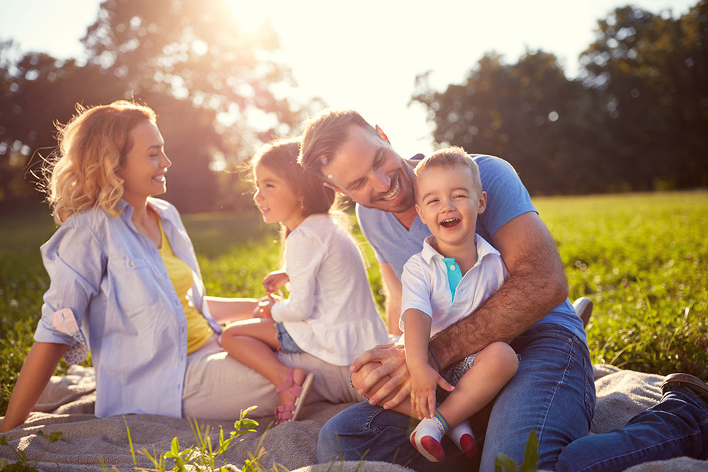 Parents sitting down with two kids on the grass laughing and smiling